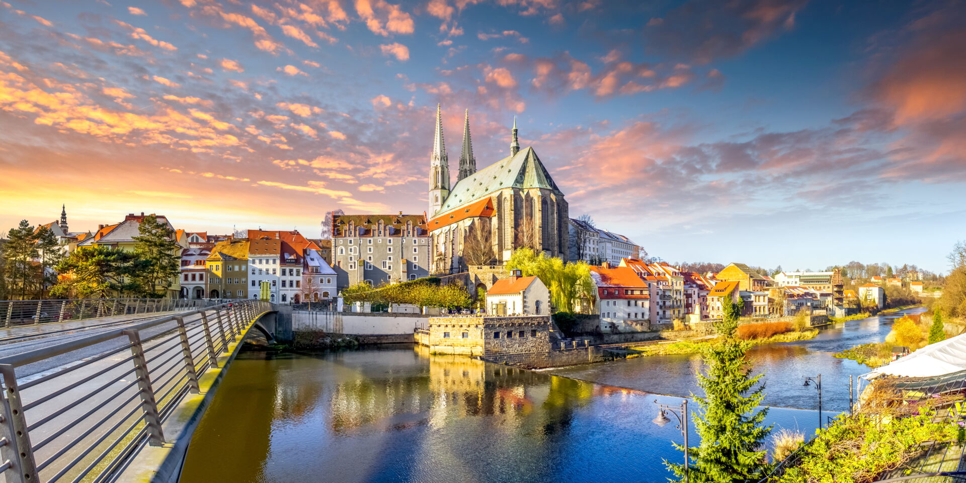 Sachverständiger Thomas Leder Ihr Gutachter in Görlitz Panoramablick auf die Altstadt von Görlitz mit der Neiße und einer Brücke bei Sonnenuntergang mit dramatischen Wolken.